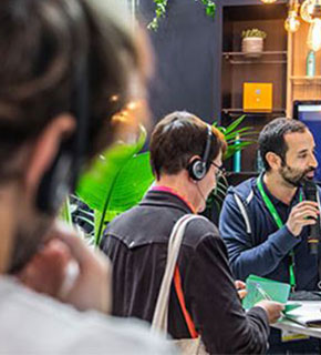 Journalist conducting an interview with a microphone in a bright, plant-filled space during the show.