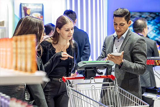 A man and two women talking next to a cart in the hallways