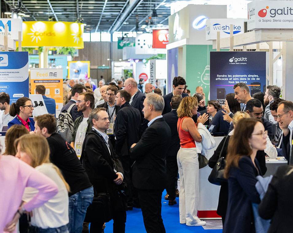 Lively view of a trade show aisle with numerous attendees engaged in discussions around exhibitor booths.