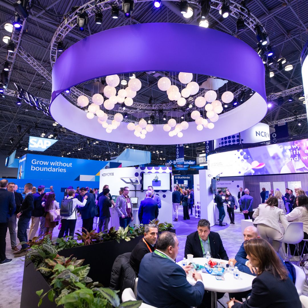 Networking and discussions among retail professionals on the NRF show floor, surrounded by exhibitor booths and innovations.