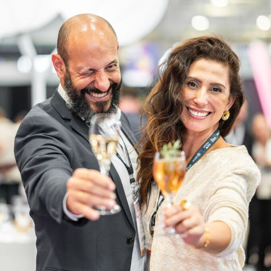 Two smiling attendees raise their glasses during a professional networking event.