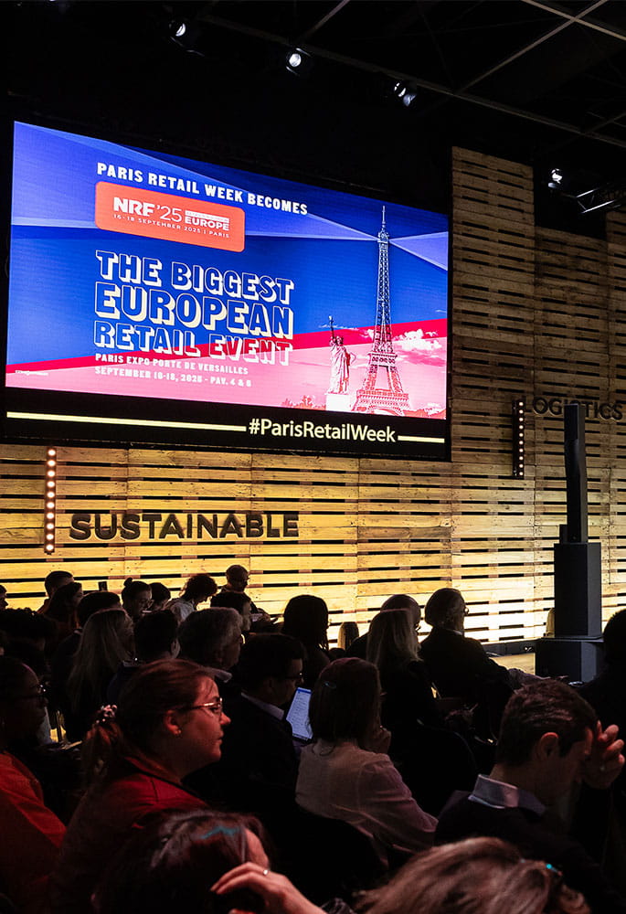 Conference at the show with a screen announcing the transition to NRF '25 Europe, featuring the slogan 'The Biggest European Retail Event'.