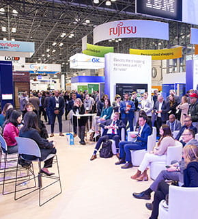 Conférence au salon NRF Big Show 2024 avec un public attentif et des stands de grandes marques en arrière-plan.