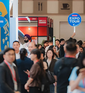 Group of participants following a guide holding an 'Expo Tour' sign at a professional trade show.