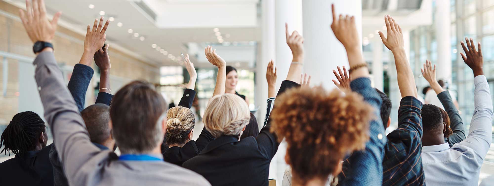 Participants raising their hands to ask questions during a conference or workshop.