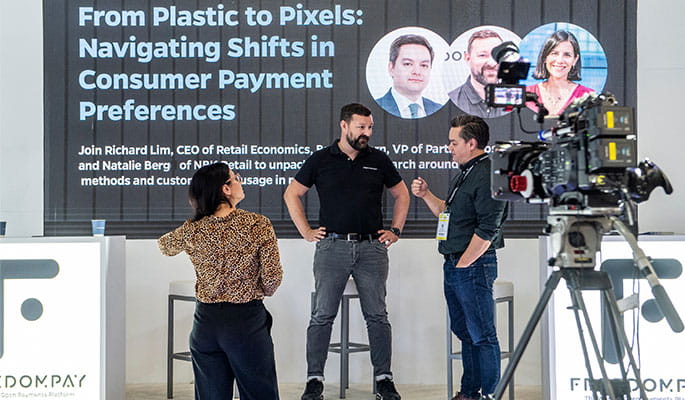 Discussion between experts during a conference on the evolution of consumer payment preferences, with a camera in the foreground.